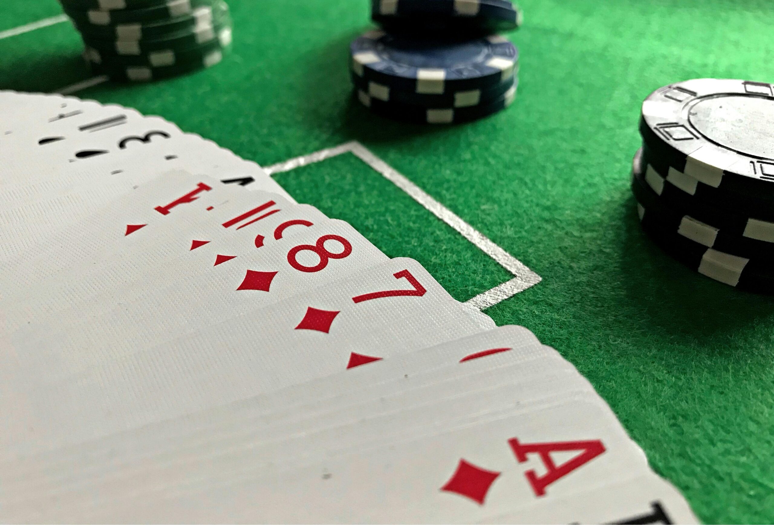 Nachaufnahme von aufgefächerten Pokerkarten auf einem Tisch, sowie Pokerchips.