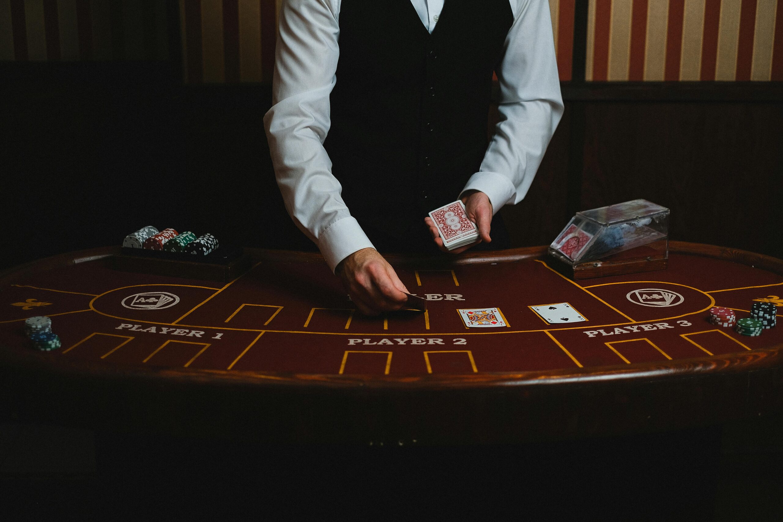 Fotografie eines Mannes im Anschnitt der Karten auf einem Pokertisch aufdeckt.