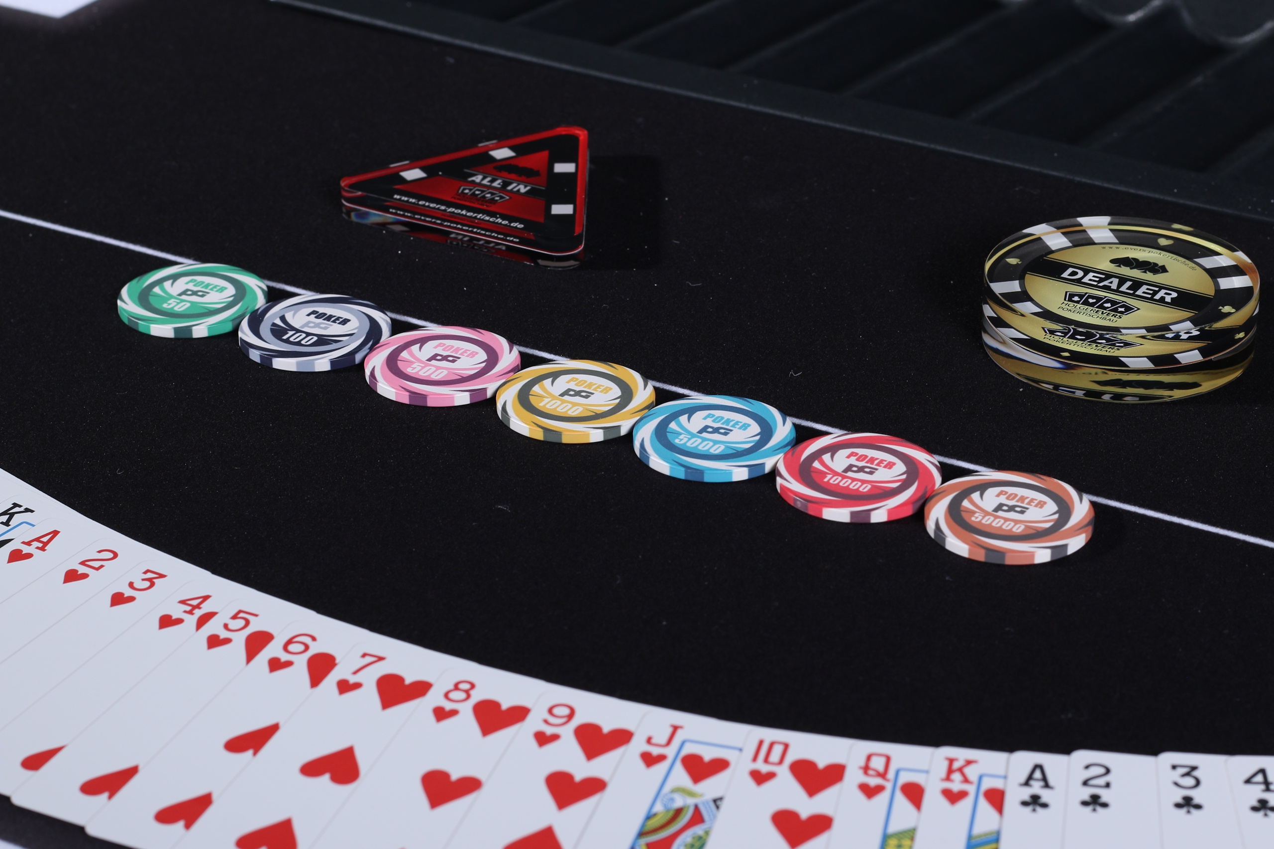 Eine saubere Anreihung von Poker Chips mit ein paar Karten im Hintergrund in einem Fächer